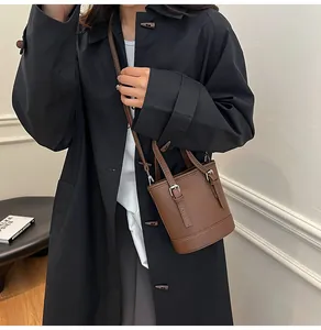 Litchi pattern leather bucket bag shown on model with adjustable strap detail