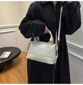 Close-up of light grey patent leather handbag with gold hardware and shoulder strap