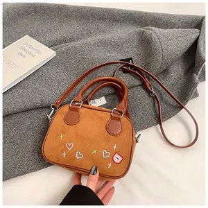Détail du sac bowling marron mat avec broderies colorées de cœur et d'ours