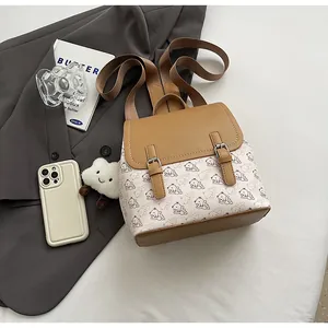 Détail d'un sac à dos crème chic avec finitions en cuir marron et motifs d'ours