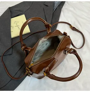 Detail of spacious dark brown Boston bag with smooth finish and adjustable shoulder strap