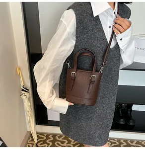 Model showing dark brown lychee grain bucket bag with silver hardware and shoulder strap