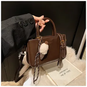 Détail du sac à main en cuir verni marron foncé avec charm glace en peluche et métal doré