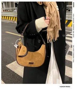 Detail of a brown suede crescent bag and matching pouch on a black coat model
