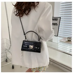 Détail du sac en cuir noir motif crocodile avec fermoir cœur argenté et fine bandoulière