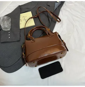 Polished brown leather bag detail with gold hardware and protective metal feet at base