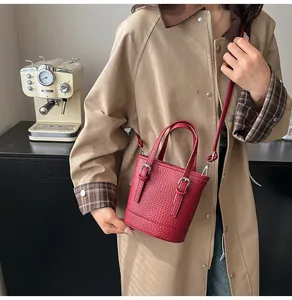 Detail of red grain leather bucket bag featuring silver buckles and crossbody strap