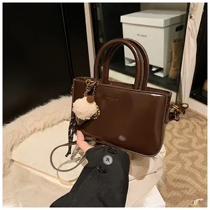 Détail du sac en cuir verni marron foncé orné d'un joli pendentif en peluche glacée