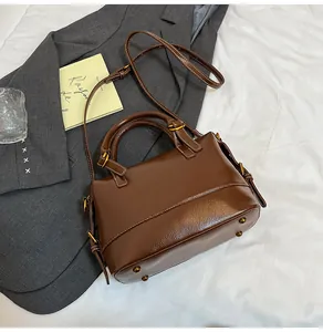 Detailed view of dark brown leather handbag with gold metal feet and adjustable strap