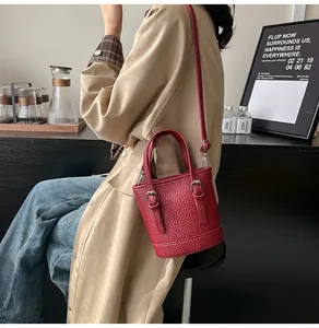 Red pebbled leather bucket bag styled with a beige trench coat for a casual daily look