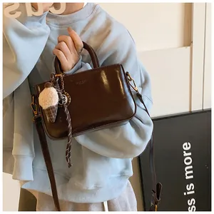 Sac à main en similicuir marron foncé avec breloque peluche porté en bandoulière
