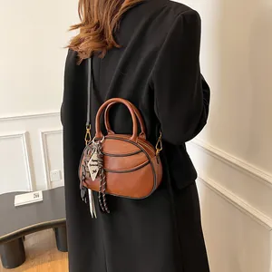 Brown leather crossbody baseball bag with dual handles and stylish hanging tag detail