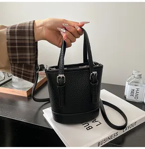 Detail of a black bucket bag with pebbled leather texture and silver metal buckles