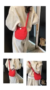 Détail du sac bandoulière en peluche rouge avec texture douce et pompon blanc décoratif