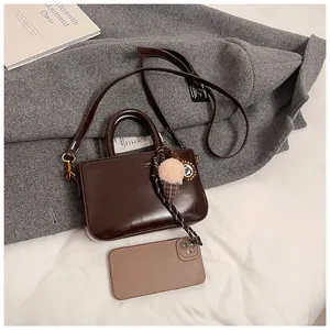 Détail d'un sac à main rétro marron foncé avec pendentif crème glacée et téléphone témoin