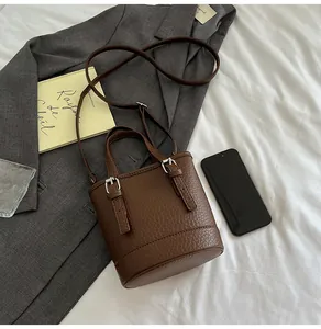 Detailed close-up of dark brown litchi pattern bucket bag on a grey office blazer