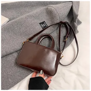 Détail du mini sac en cuir poli marron foncé avec fermoirs dorés et poignée chic