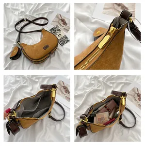 Detail of camel suede crescent bag with brown leather strap and mini round charm