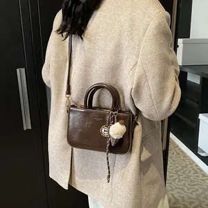 Sac à main en cuir marron foncé avec charm glace en peluche et étiquette en métal