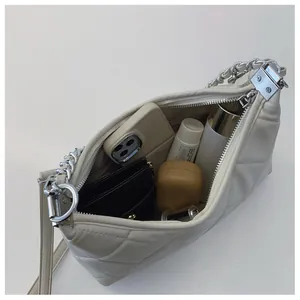 Capacity view of beige quilted handbag with silver chain and daily essentials