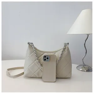Detailed close-up of a beige quilted crossbody bag with metal chain and leather straps