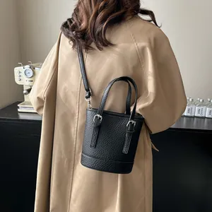 Minimalist black pebble leather bucket bag with silver hardware and top handle for women