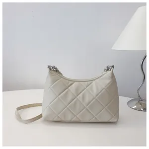 Detail of cream quilted crossbody bag with silver chain strap and modern texture