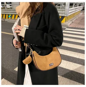 Detail of caramel suede crescent bag featuring a fashion plaque and small coin purse charm
