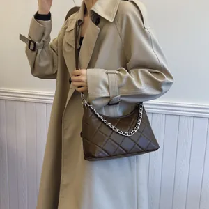 Quilted coffee brown shoulder bag with silver chain strap shown on a khaki coat