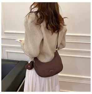 Deep brown matte suede hobo bag with a gold D-charm shown on a shoulder-carry model