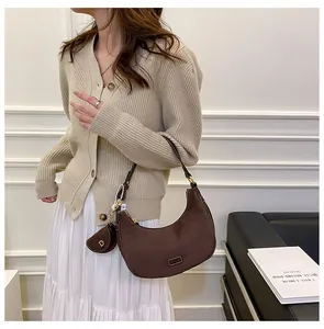 Detail of coffee suede crescent bag with matching small pouch on a stylish model