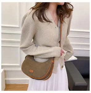 Olive green suede crescent shoulder bag with brown leather trim shown on a model