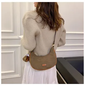 Detail of vintage brown suede crescent bag with metal logo and small coin purse attachment