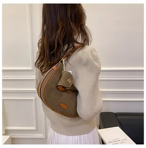 Detailed close-up of a brown suede saddle bag with gold D-charm and mini pouch