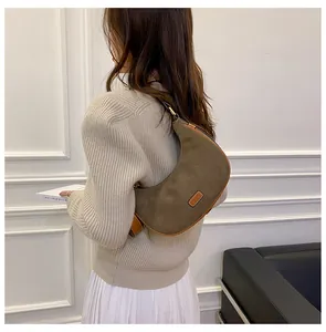 Detail of olive green suede crescent bag with brown leather trim and metal hardware