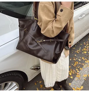 Detail of dark brown vintage PU leather tote bag with gold hardware and slim straps