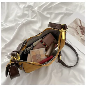 Macro view of brown suede crescent bag interior showing cosmetics and gold hardware details