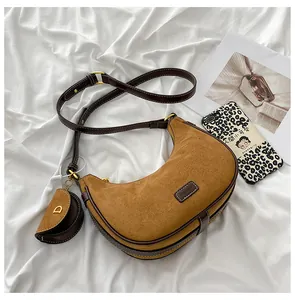 Close-up of frosted brown crescent bag featuring metal buckle and mini round coin purse