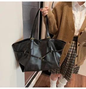 Detailed view of a black vintage leather tote bag worn by a model in a casual setting