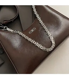 Detail of dark brown leather underarm bag featuring silver chain and metal BB logo