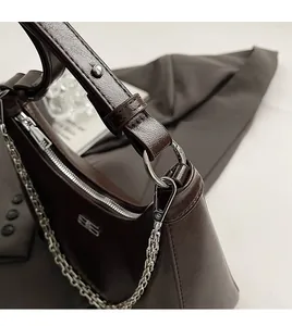Close-up of silver chain strap and metal hardware on dark brown textured leather bag