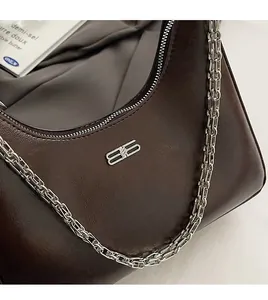 Close-up of vintage dark brown faux leather bag featuring silver metal B logo and chunky chain