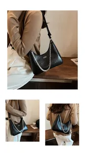 Detail of black crackle leather underarm bag with silver chain and metal logo accent