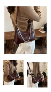 Detail view of burgundy underarm bag with silver chain strap and metal logo accent