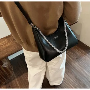 Close-up of black leather hobo bag with silver chain detail on a minimalist background