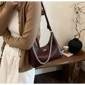 Detail of burgundy leather crescent shoulder bag featuring silver B-logo and chain strap