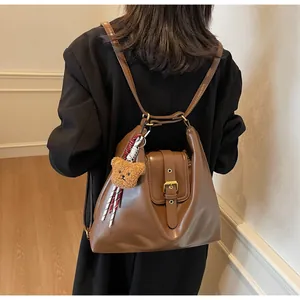 Rear view of a vintage brown leather multi-way backpack with a cute plush bear charm