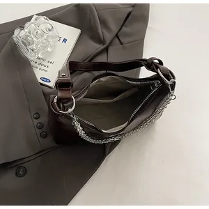Close-up of dark brown underarm bag with silver zipper, interior pocket, and chain