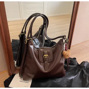 Macro shot of dark coffee retro hobo bag with teddy charm and zip detailing