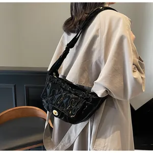 Detailed view of black patent leather saddle bag with quilted pattern and gold twist lock